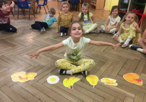 Dziewczynka ma rozłożone przed sobą obrazki z żółtymi rzeczami